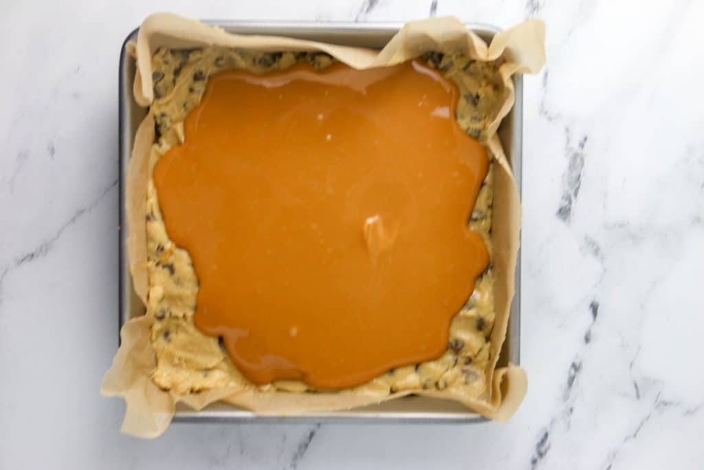 caramel poured over the cookie dough in the pan