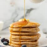stack of greek yogurt pancakes with maple syrup poured over the top