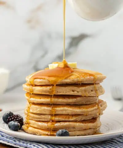 stack of greek yogurt pancakes with maple syrup poured over the top