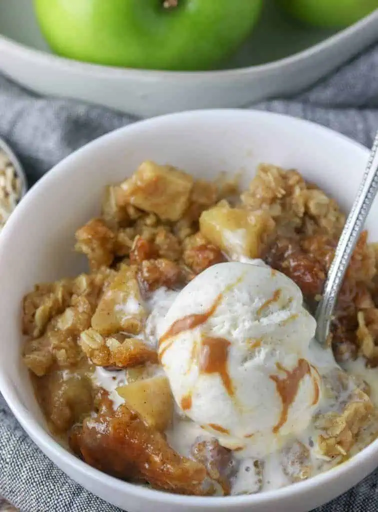 bowl of apple caramel crisp topped with vanilla icecream
