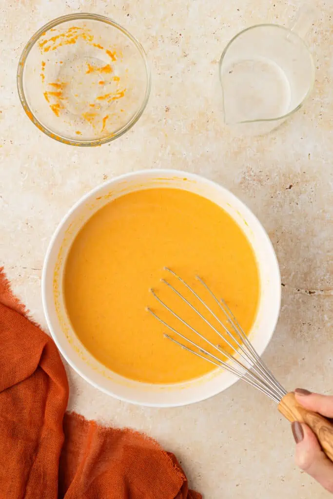 pumpkin wet mixture in a bowl with a whisk
