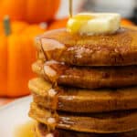 stack of pumpkin pancakes being drizzled with maple syrup