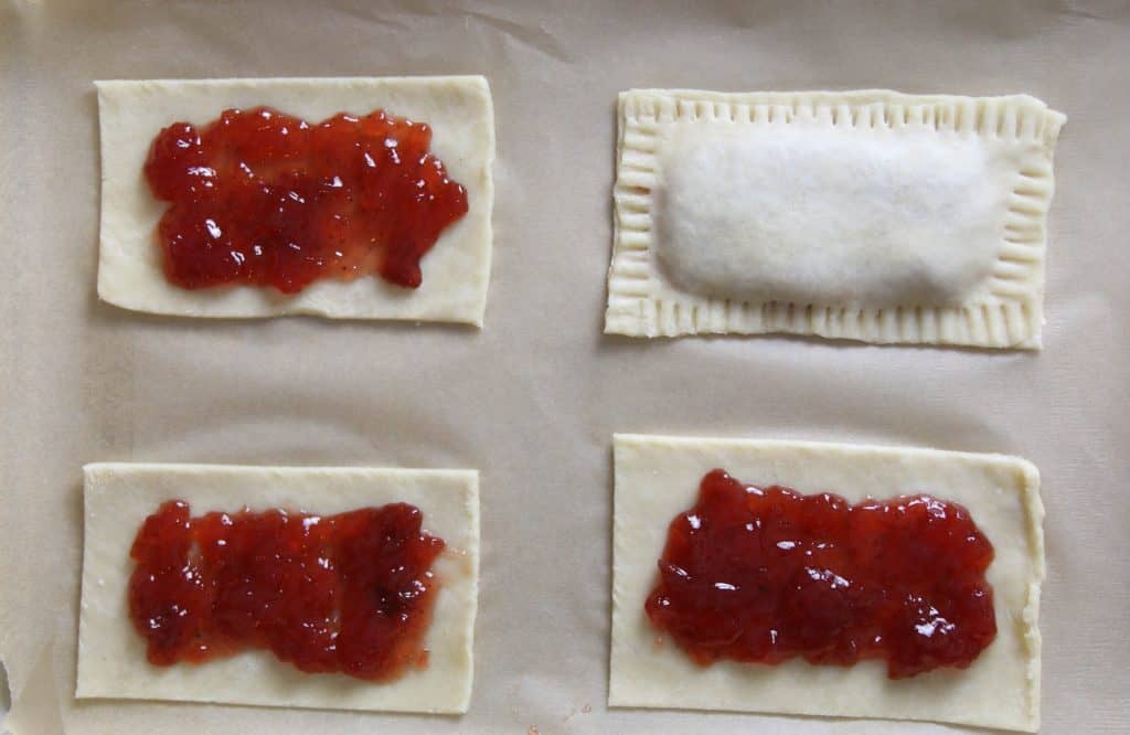 four strawberry poptarts with one poptart with top dough added and crimped