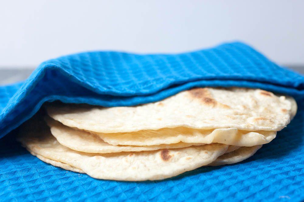 stack of flour tortillas wrapped in a blue napkin