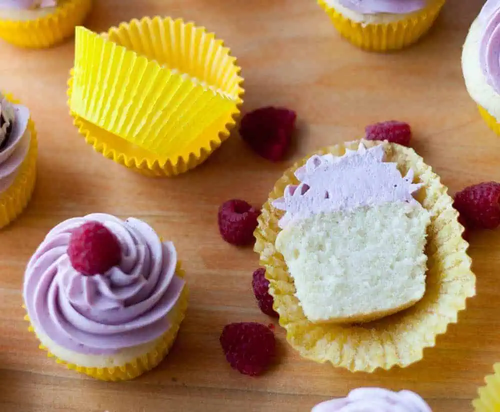 Fluffy Lemon Cupcakes with berry buttercream cupcake cut in half and yellow cupcake liners