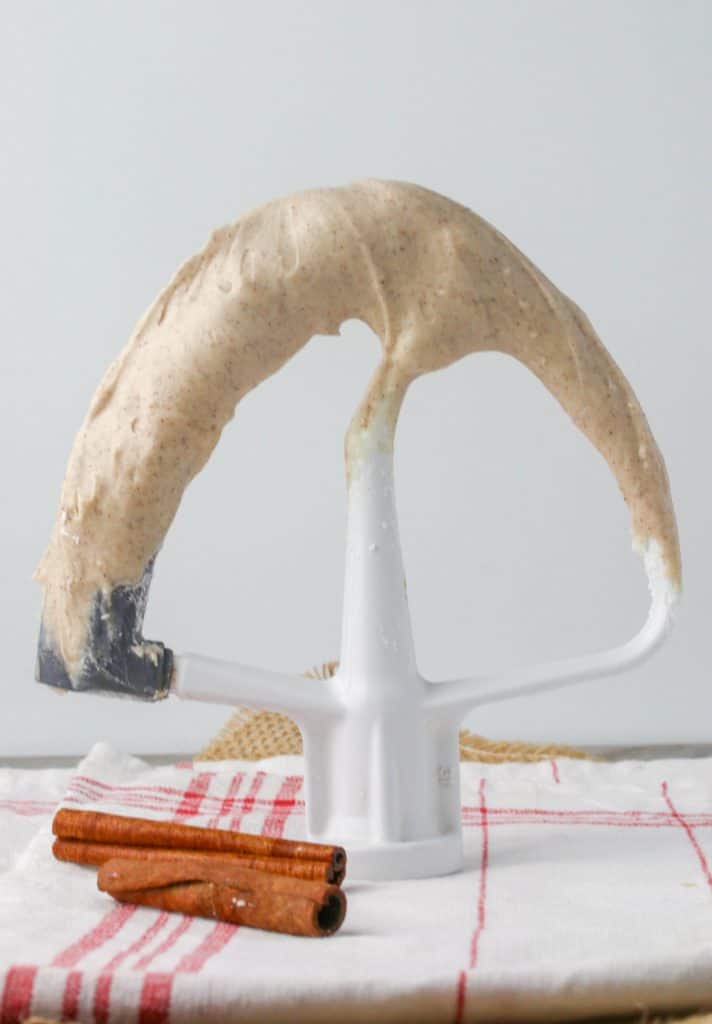 a mixer paddle attachment with cinnamon cream cheese frosting on it