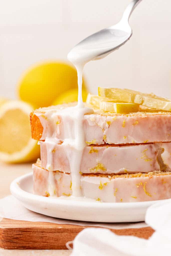 three slices of lemon bread stacked with lemon glaze drizzled over