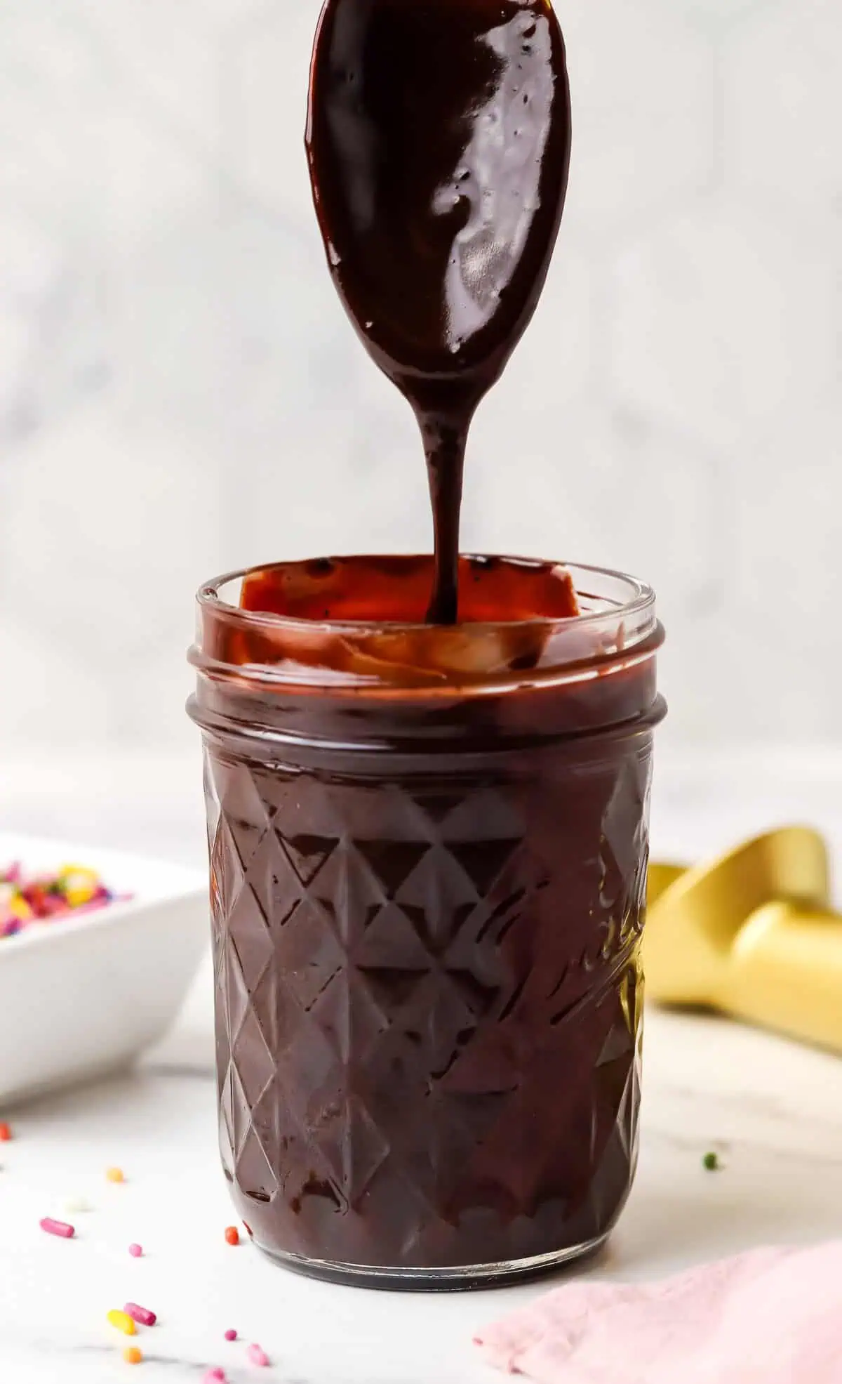 a spoon dipped into a jar of hot fudge sauce