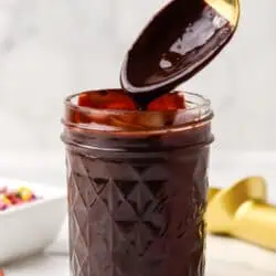 a spoon dipped into a jar of hot fudge sauce