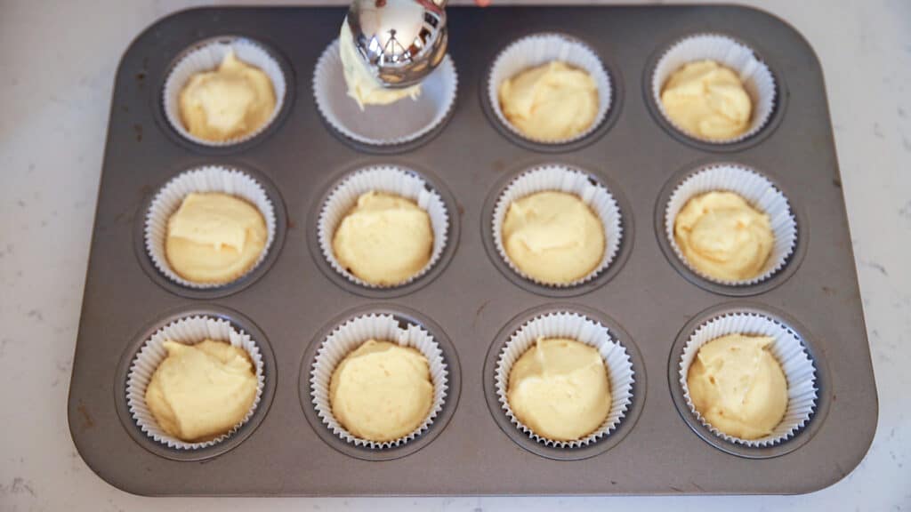 unbaked vanilla cupcake batter scooped into cupcake tin