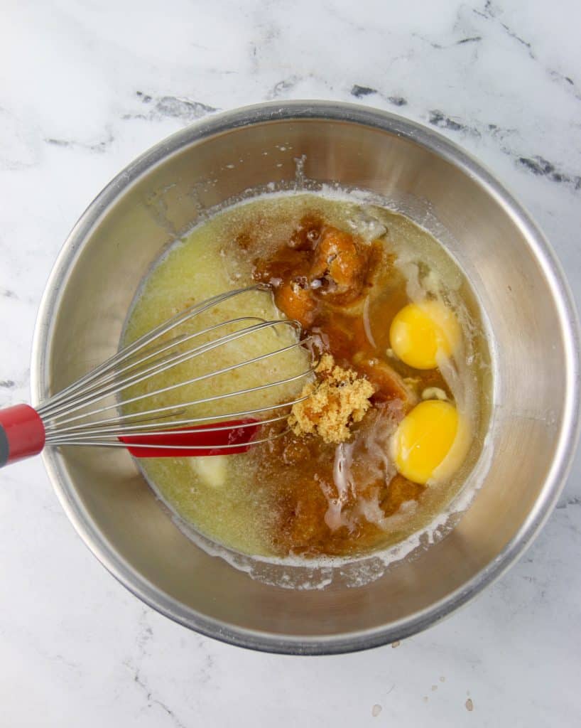 bowl of sugar, butter, and eggs with a whisk