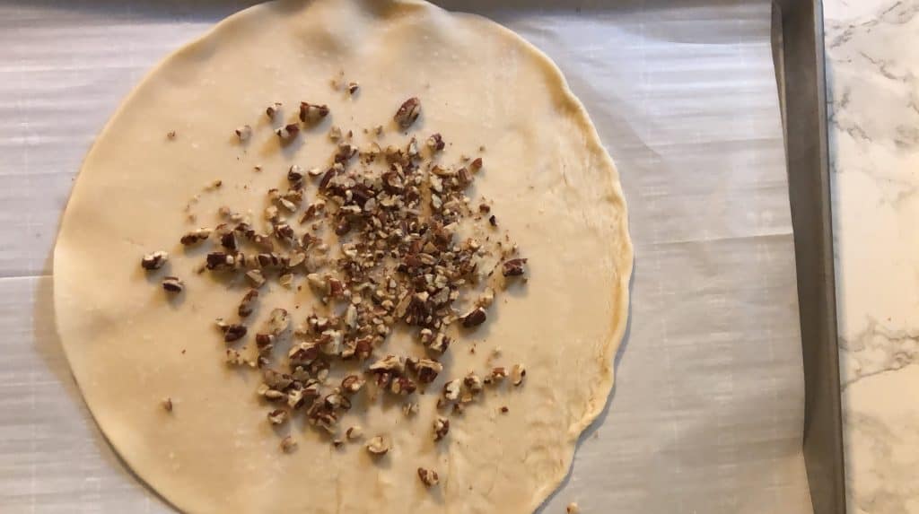 Pie dough topped with pecans