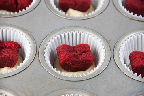 two red velvet hearts standing upright in a cupcake well