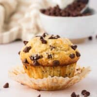 chocolate chip muffin with paper liner pulled away from it