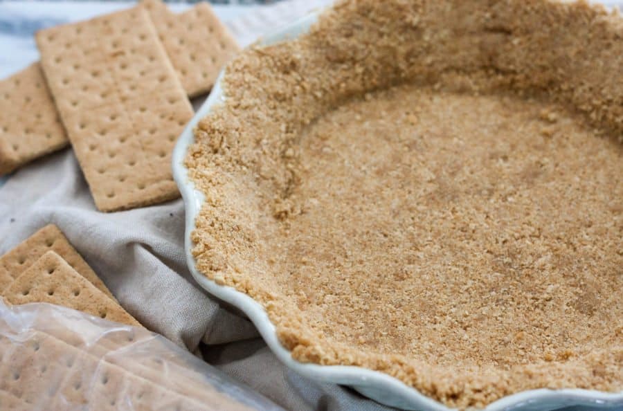 graham cracker crust in a pie plate with graham crackers next to it