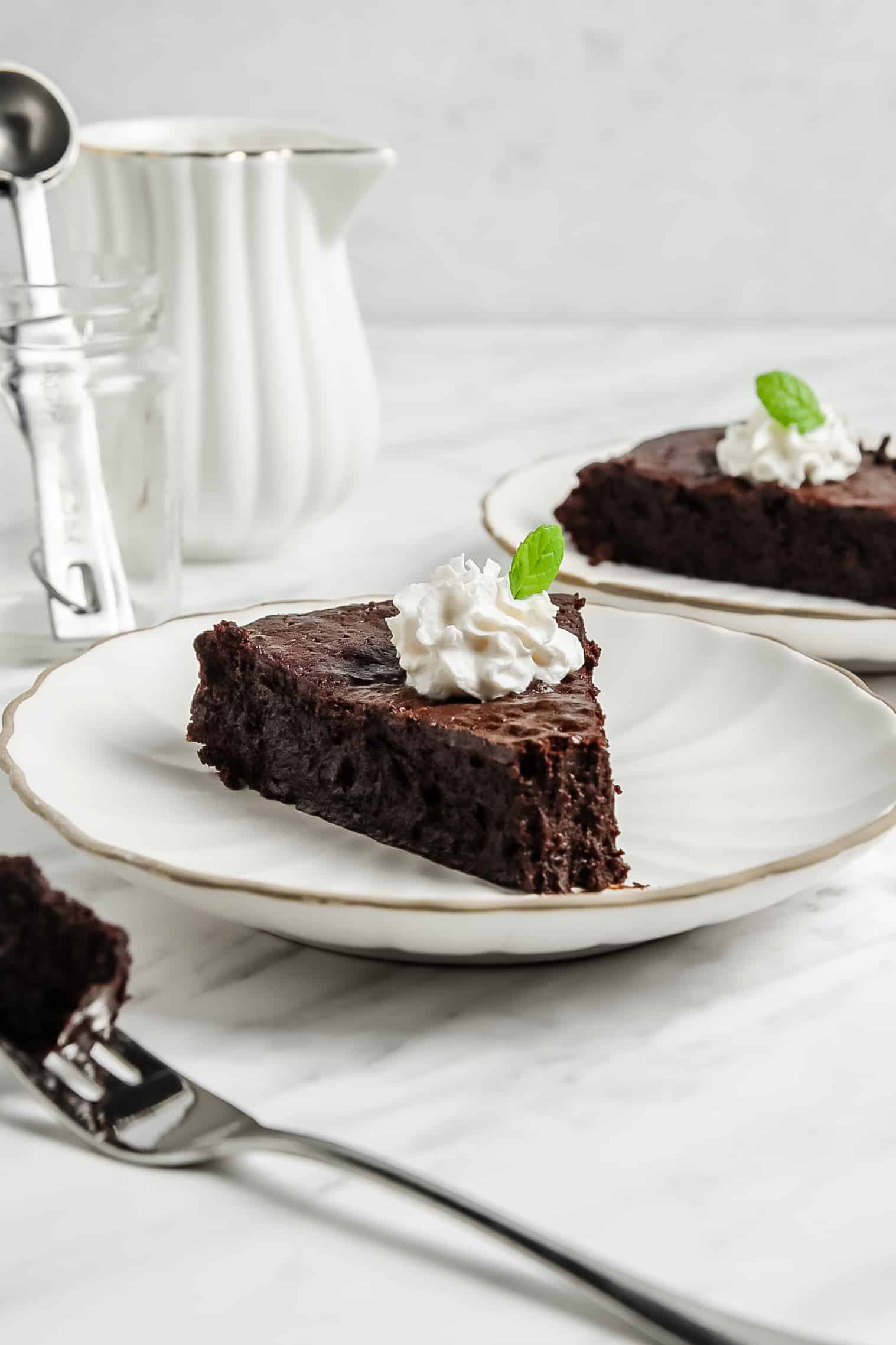 slice of flourless chocolate cake on a plate topped with whipped cream and mint
