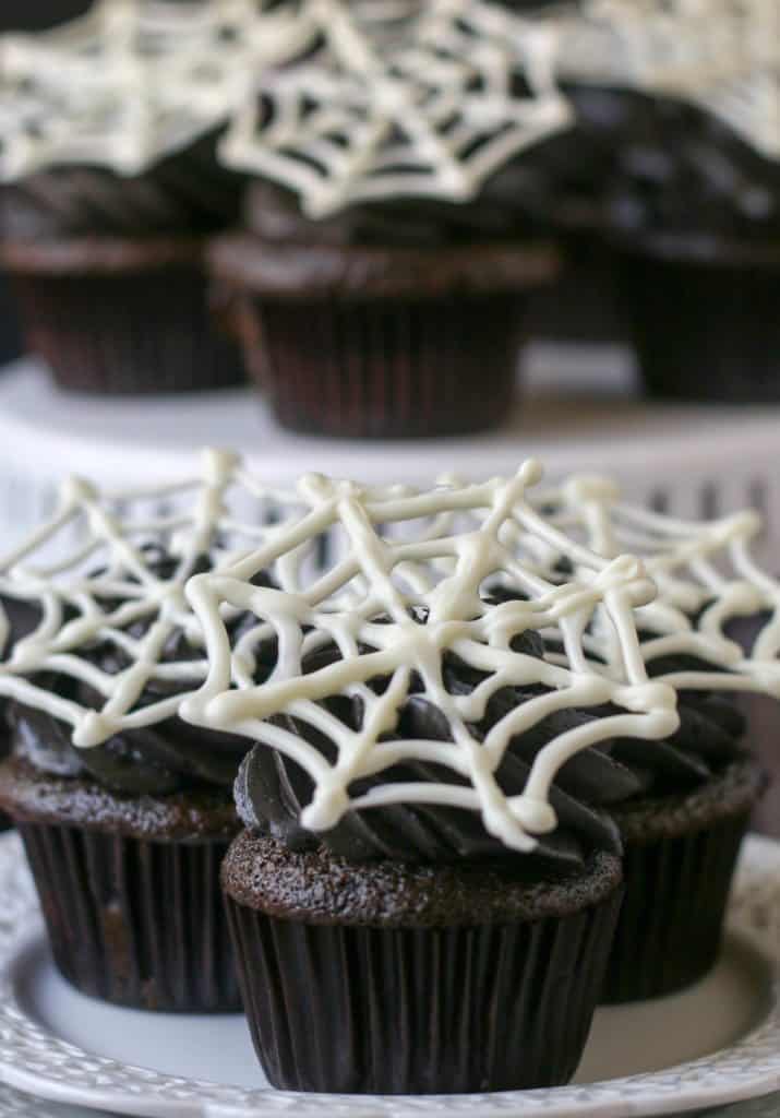 three spiderweb cupcakes on a plate