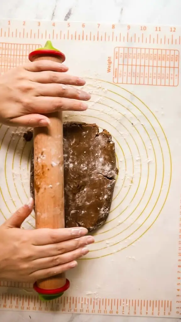 gingerbread cookie dough being rolled out with a rolling pin