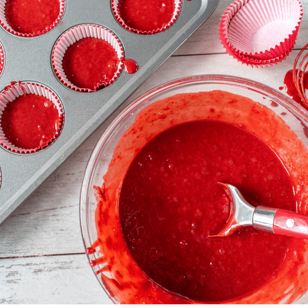 red velvet cupcake batter in a bowl and a muffin tin with batter in liners