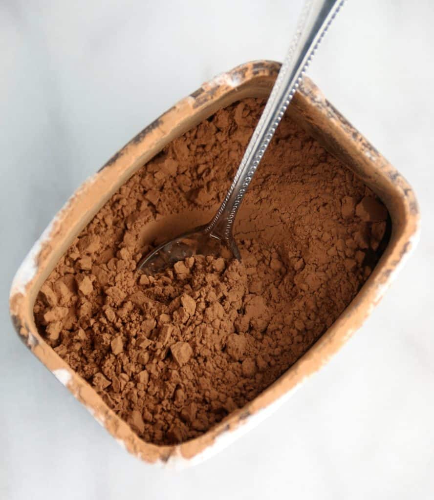 A container of cocoa powder with a spoon in it
