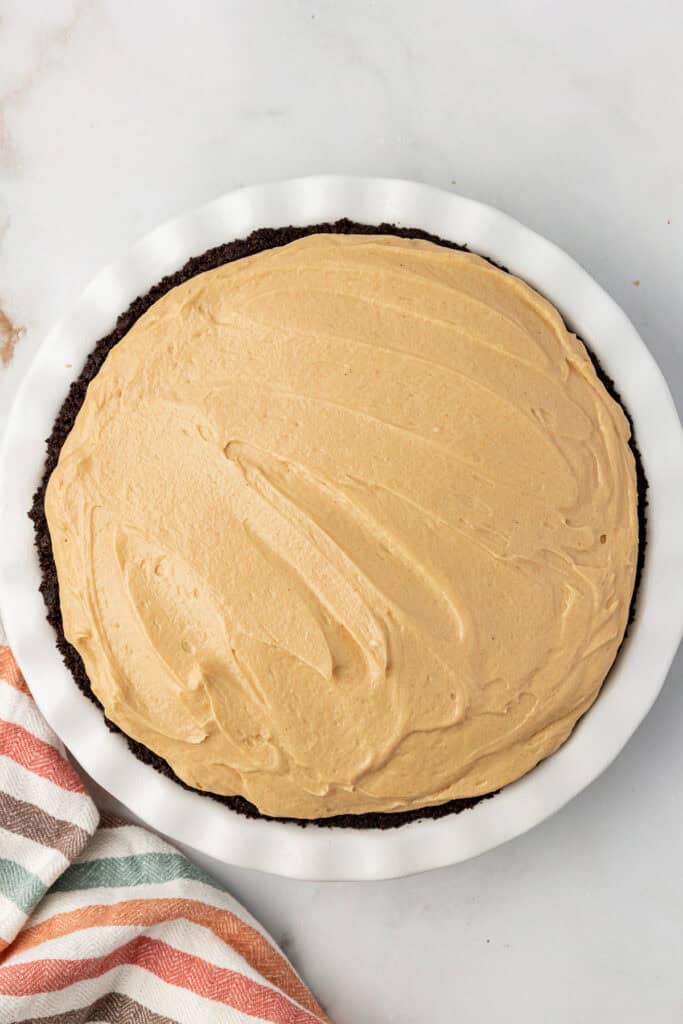 no bake peanut butter pie mixture spread into oreo cookie crust in pie plate