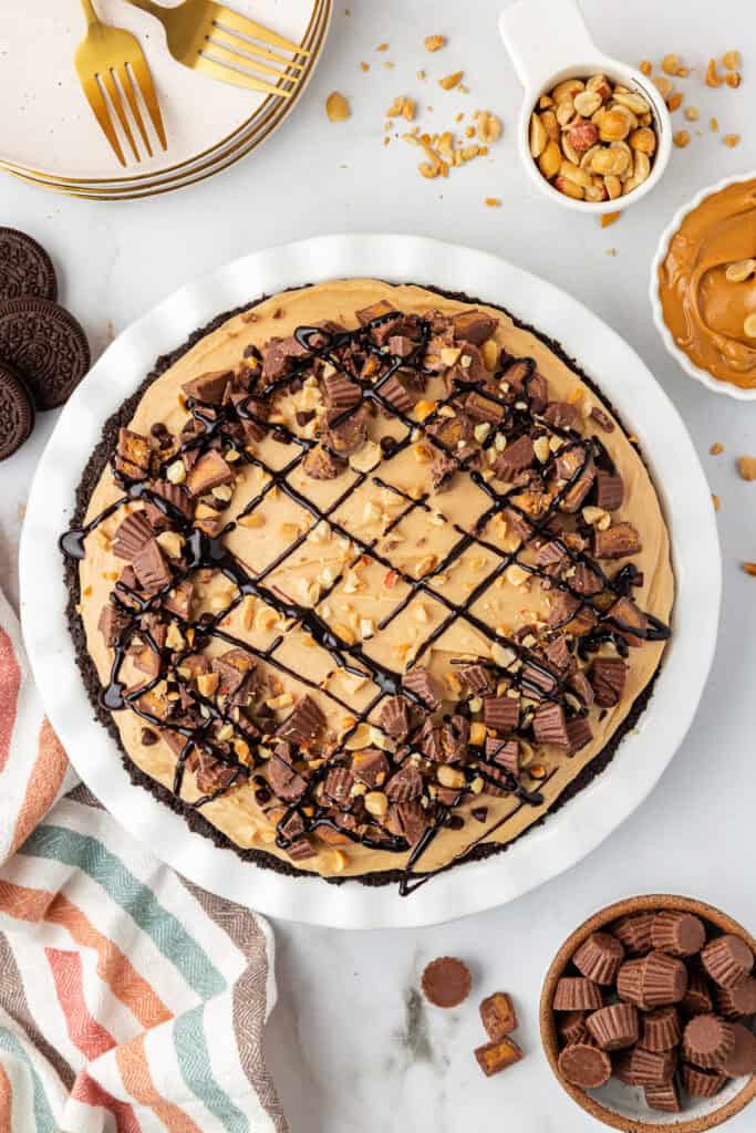 no bake peanut butter pie garnished with chocolate sauce, and peanut butter cups
