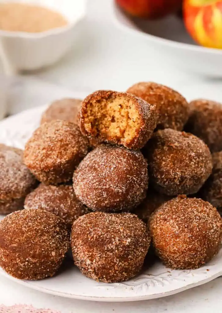 Apple cider doughnut holes a stack of apple cider donut holes with one that has a bite taken out of it