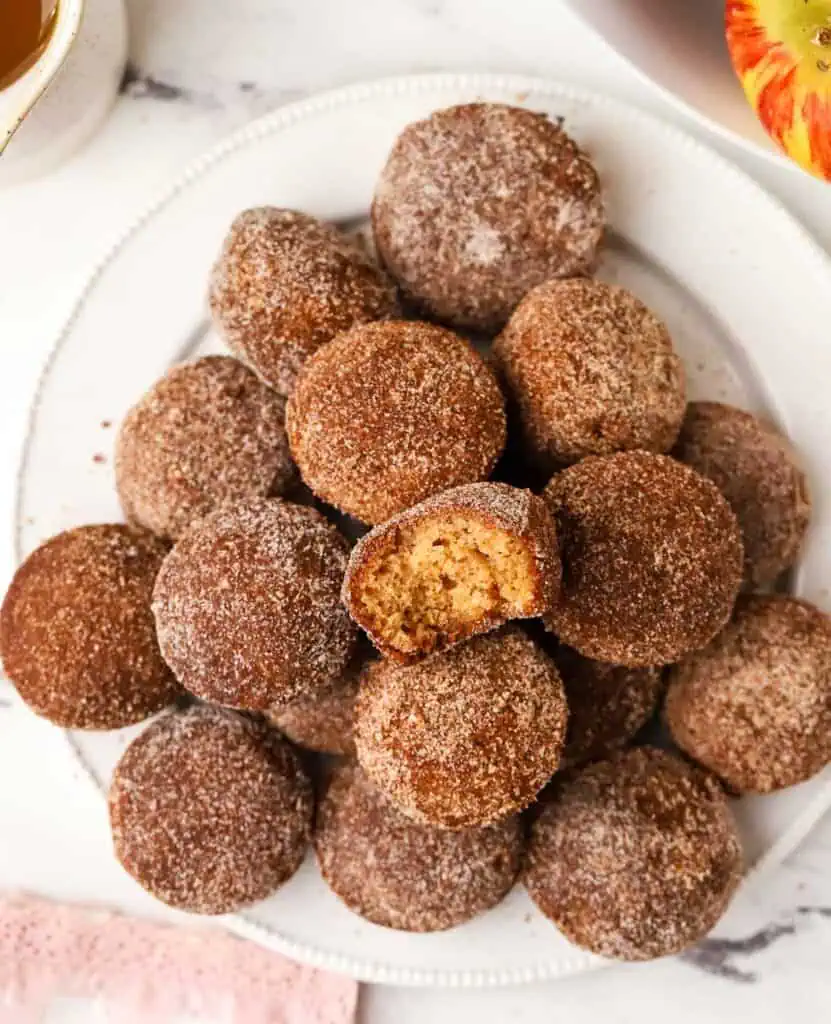 Apple Cider Donut Holes a plate of apple cider donut holes with one that has a bite taken out of it
