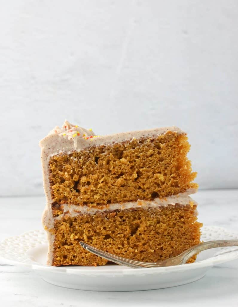 slice of pumpkin cake standing up on a plate with a fork