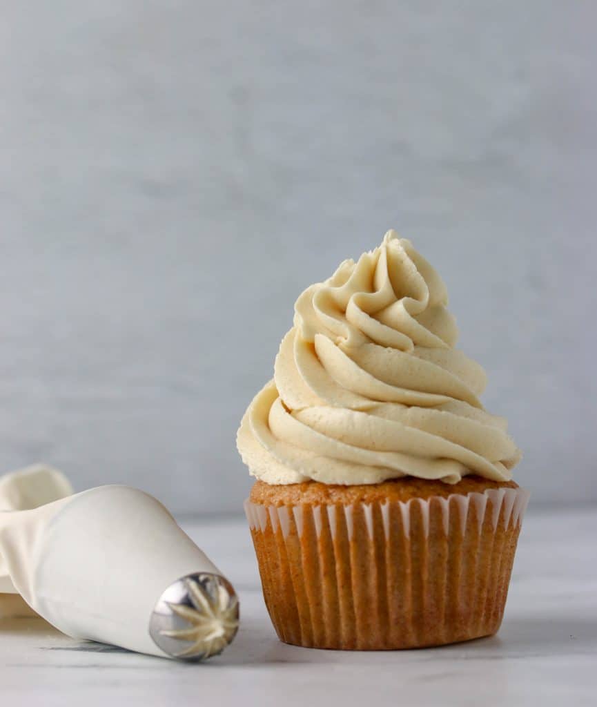 cupcake topped with brown sugar buttercream and a piping bag next to it