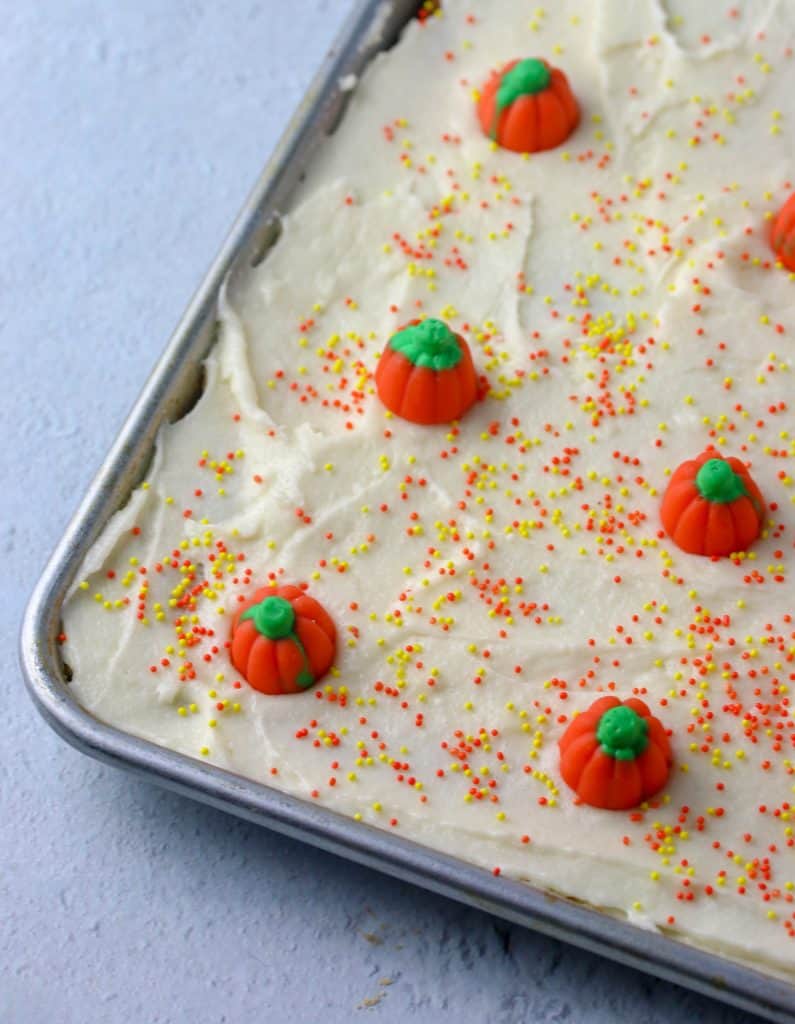 pumpkin bars with cream cheese frosting topped with sprinkles and candy pumpkins