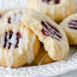 raspberry thumbprint cookies on a plate with a bite missing