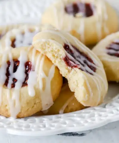 raspberry thumbprint cookies on a plate with a bite missing