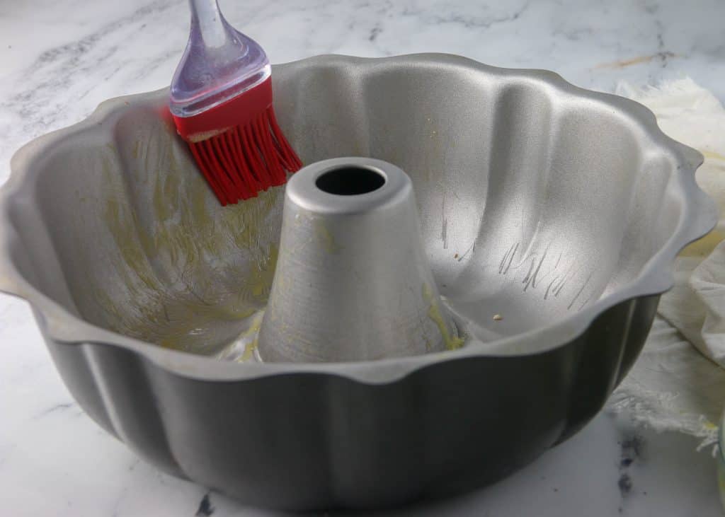 melted butter brushed on a bundt pan with a red pastry brush