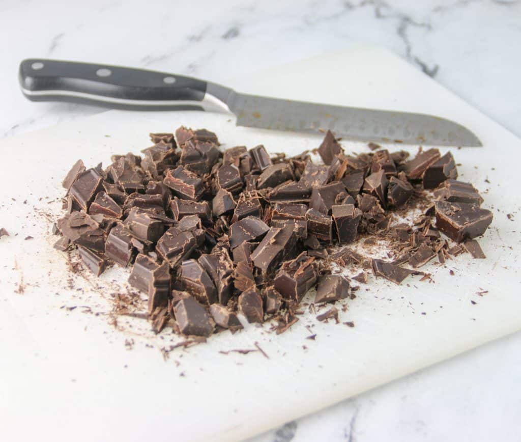 chopped up chocolate in a cutting board with a knife