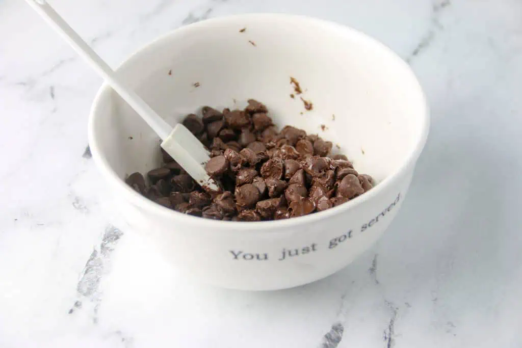 bowl of semi melted chocolate chips with a spatula
