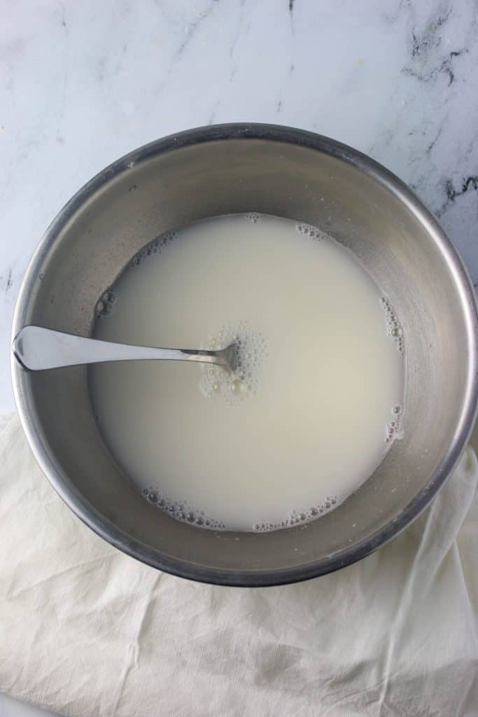 water and sourdough starter in a mixing bowl with a fork