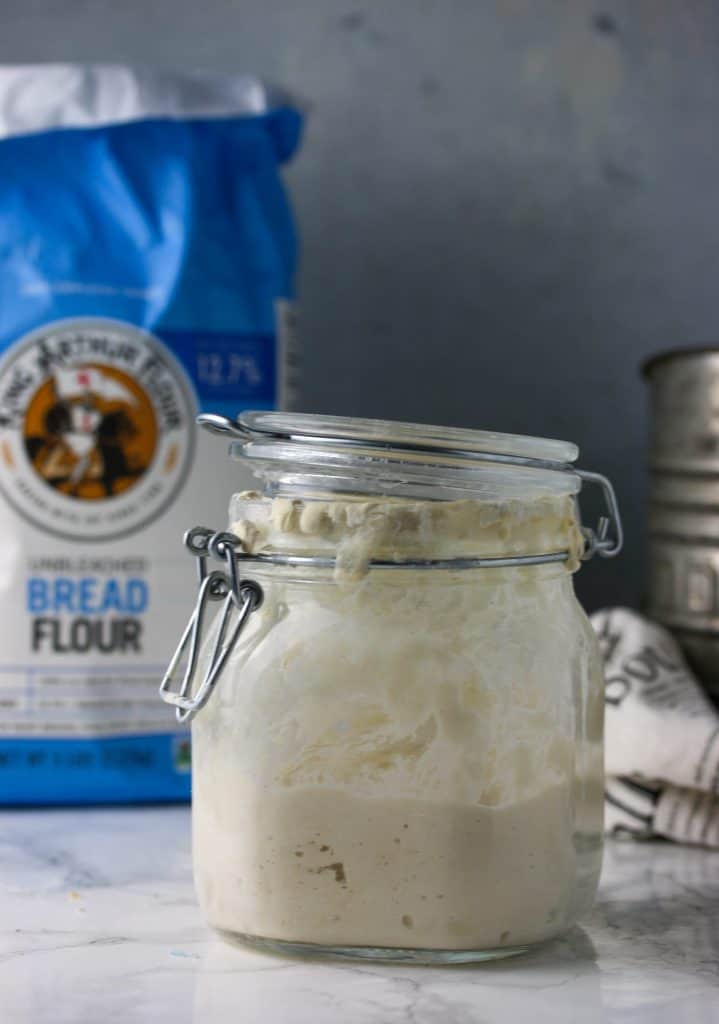 bag of flour, sourdough starter in a glass jar