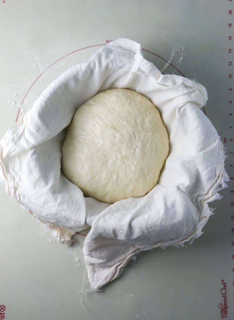 sourdough bread dough in a towel lined bowl