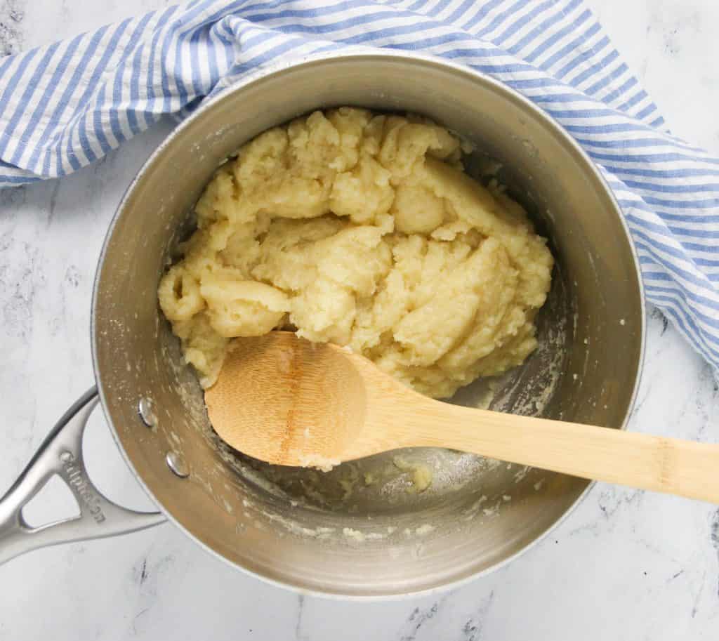 choux pastry dough in a saucepan with a wooden spoon