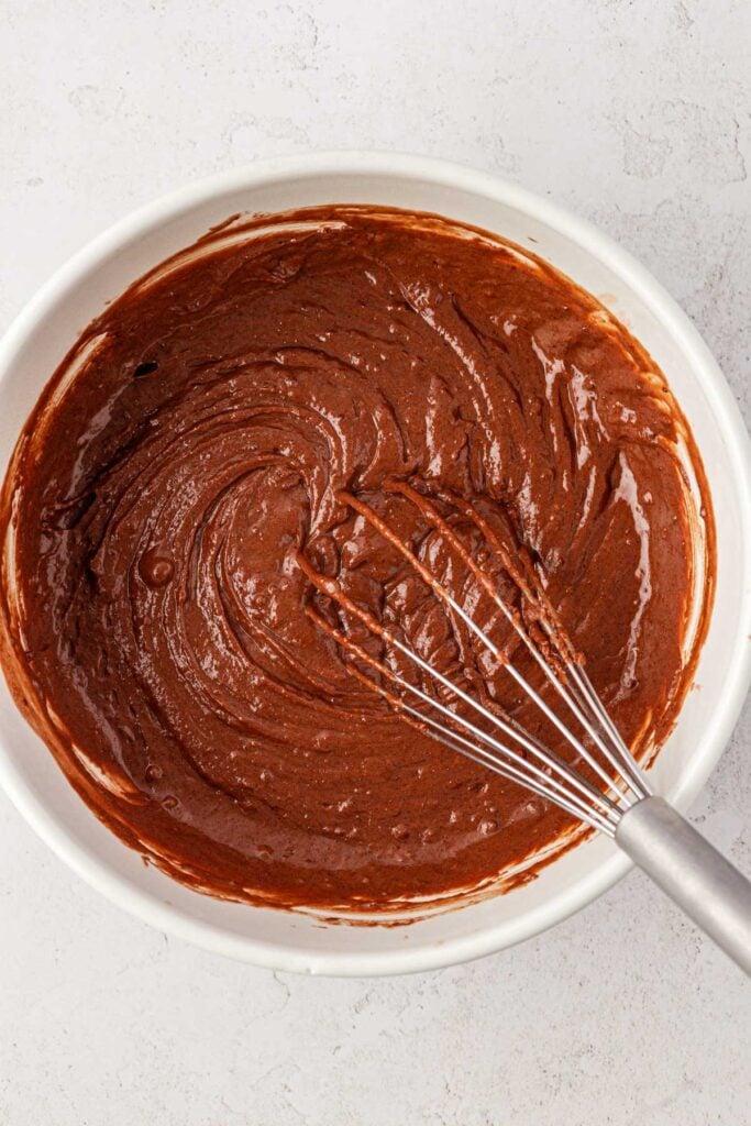 chocolate cake batter in a bowl with a whisk
