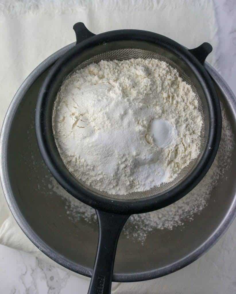 dry ingredients in a sifter set over a bowl