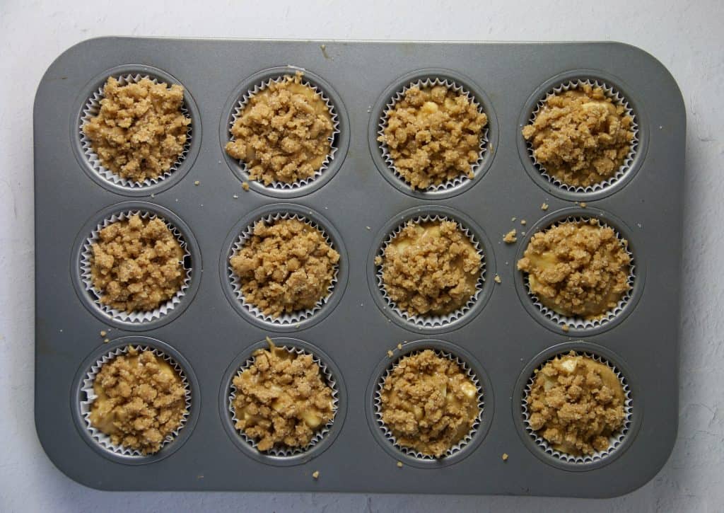 apple muffins with crumb topping sprinkled on top unbaked in muffin tin