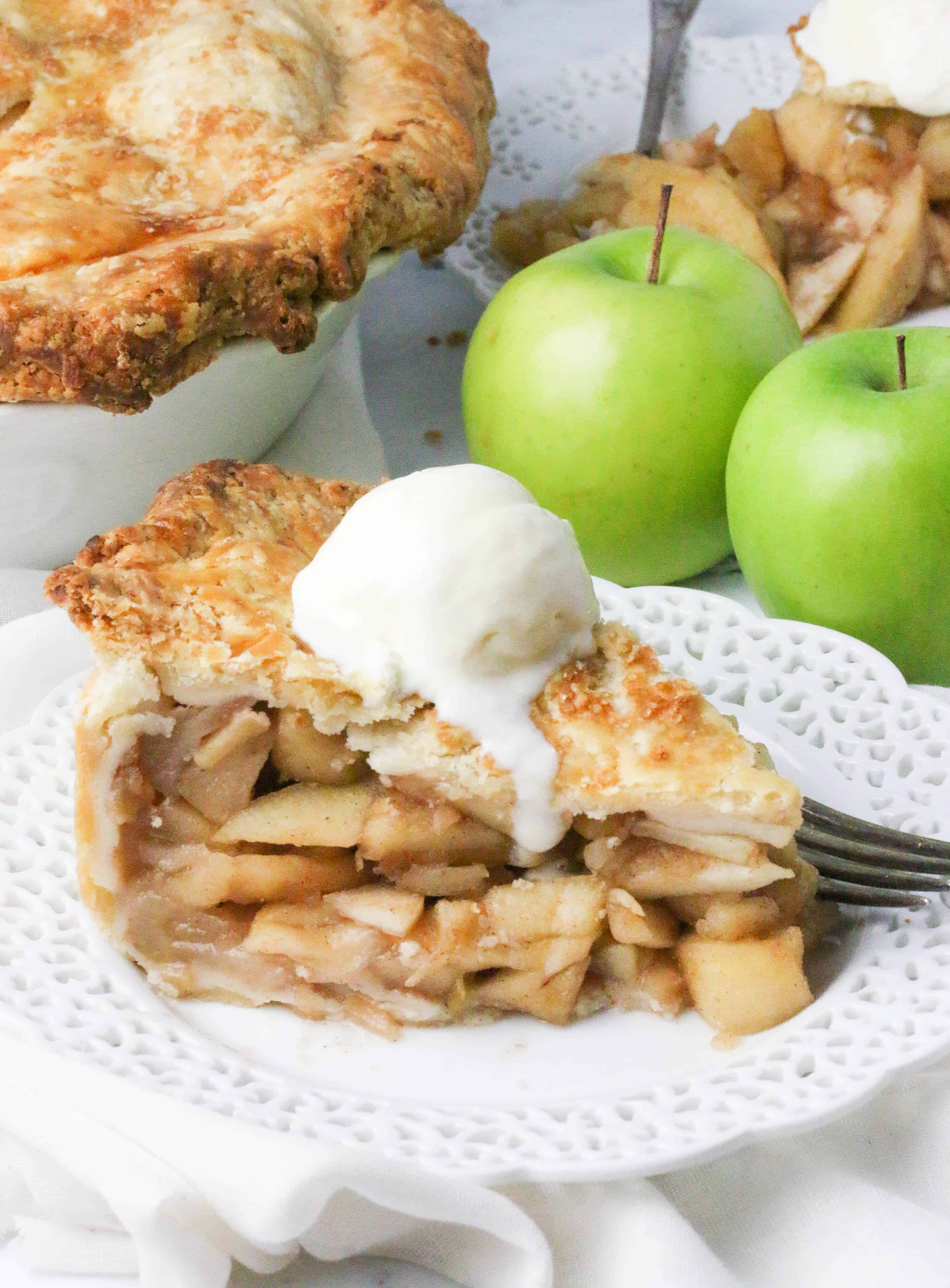 slice of deep dish apple pie on a plate topped with vanilla ice-cream