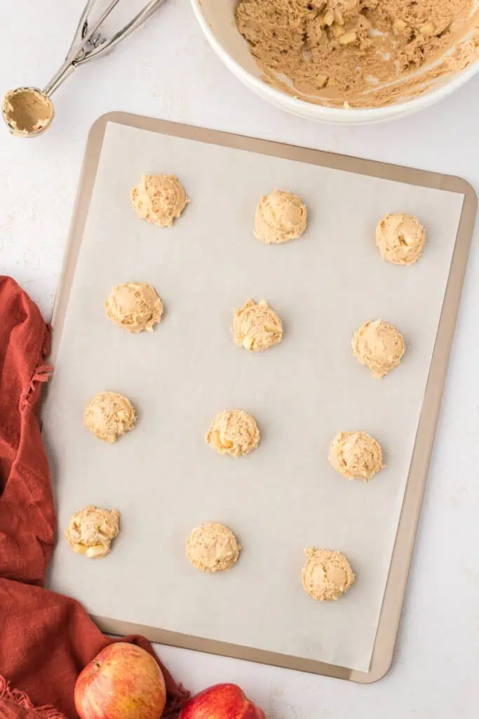 scooped apple cider cookie dough balls on a parchment lined baking sheet