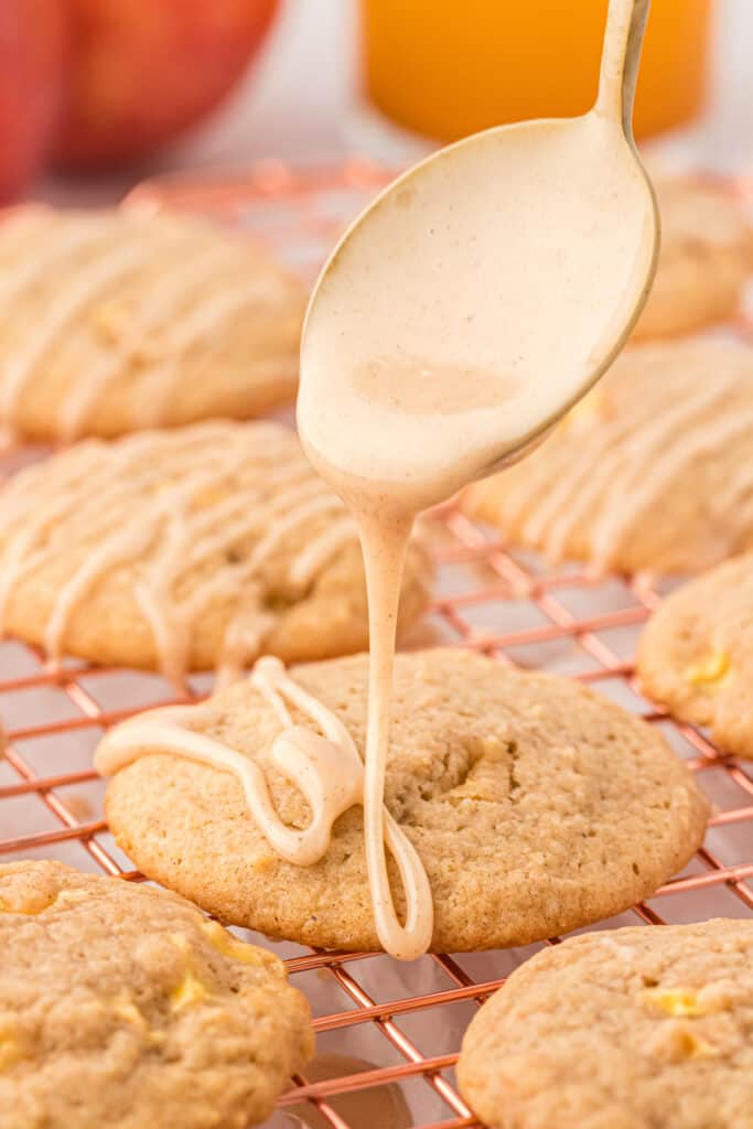 apple cider icing being drizzled over an apple cider cookie