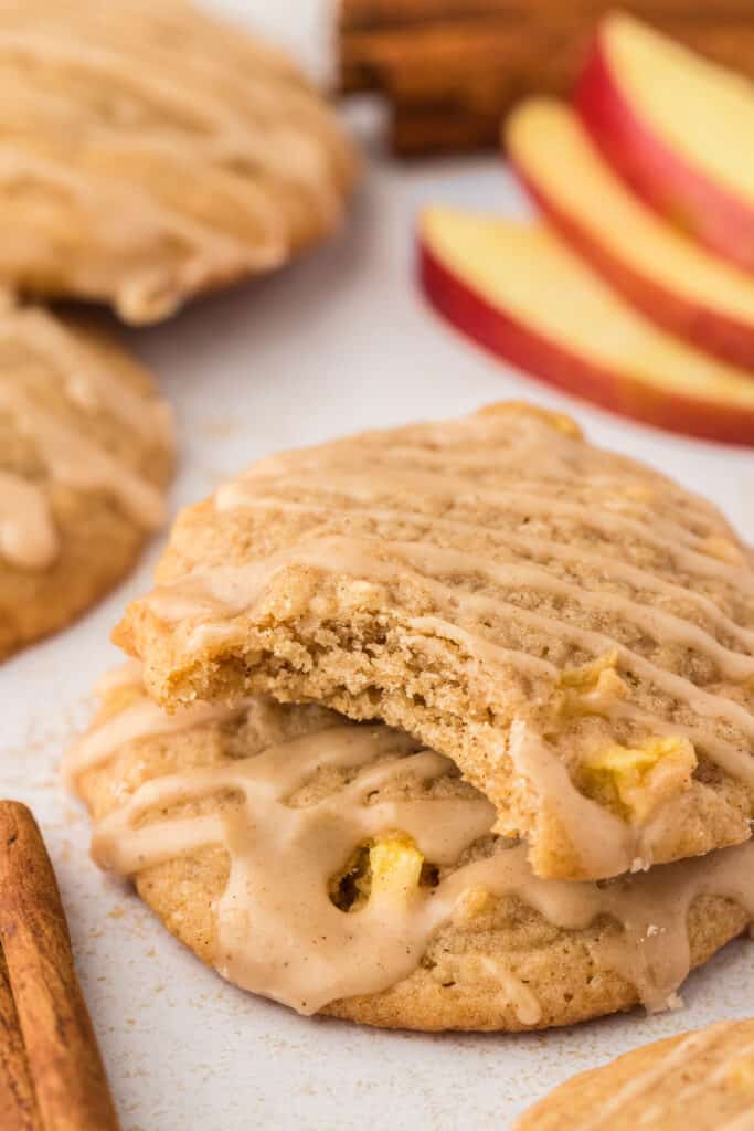 two apple cider cookies stacked on top of each other with a bite taken out of the top cookie