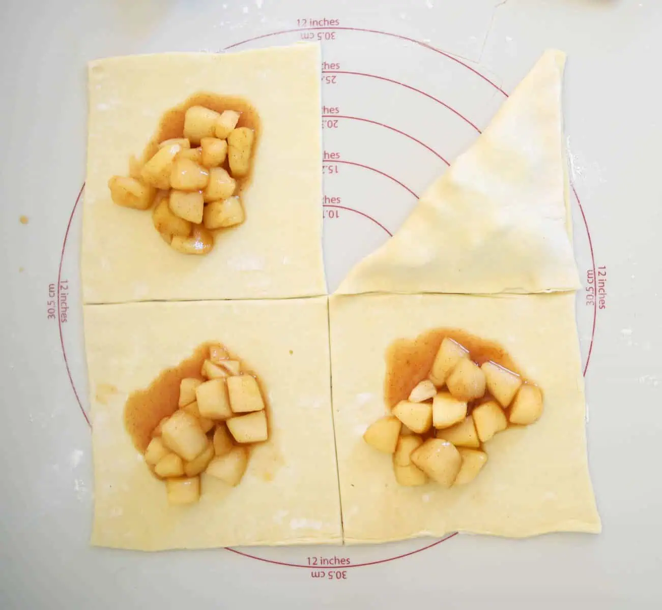 four squares of puff pastry with filling in the center, and one folded over to make a triangle