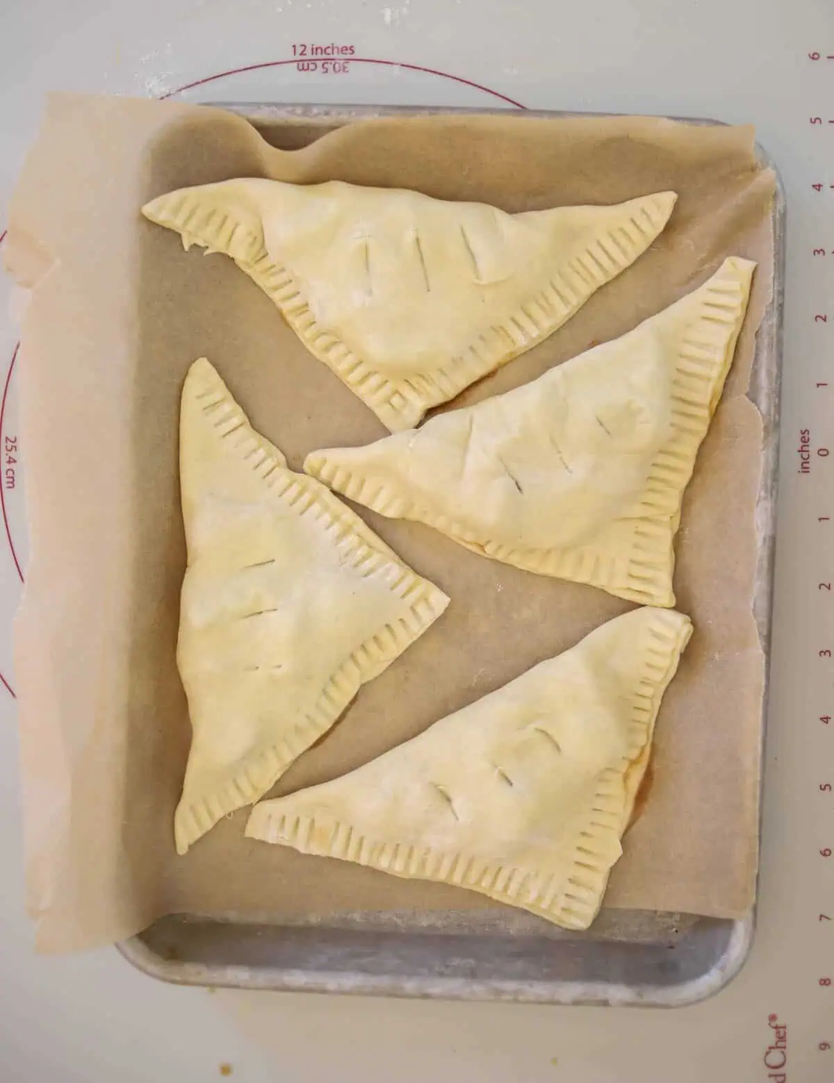 four unbaked turnovers on a baking sheet