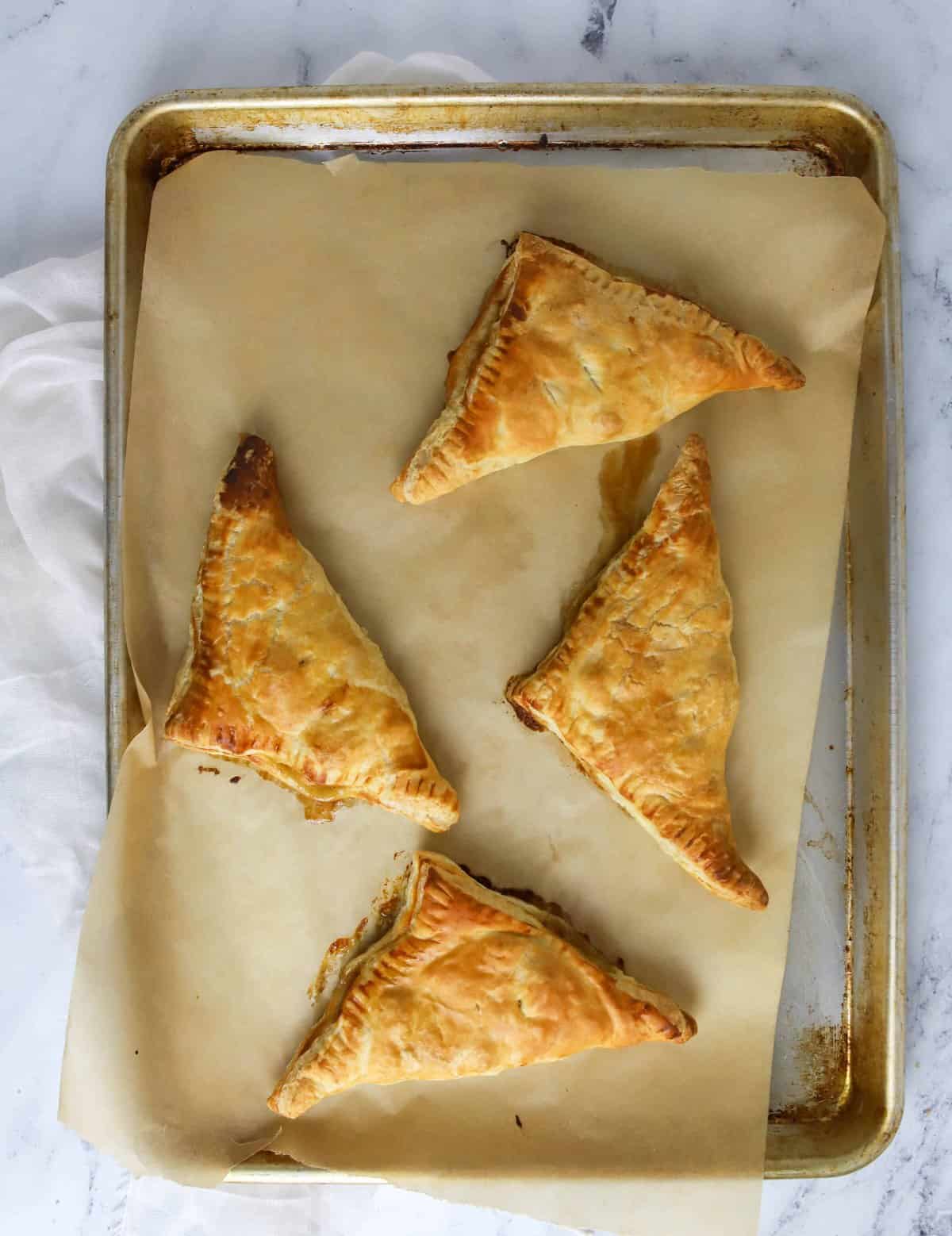 four baked turnovers on a baking sheet